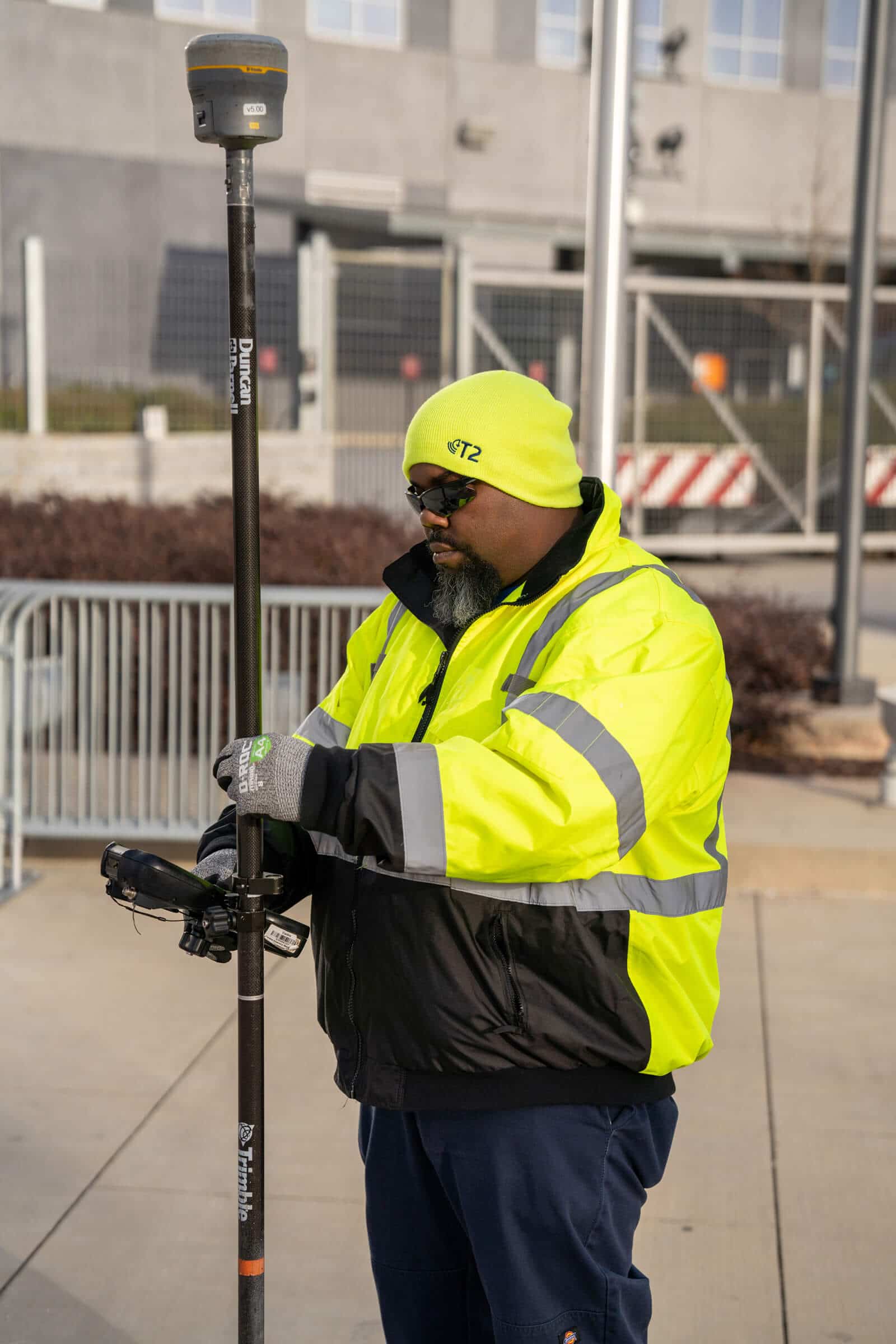 Man wearing T2 Utility Engineers safety clothing using survey equipment in an urban environment