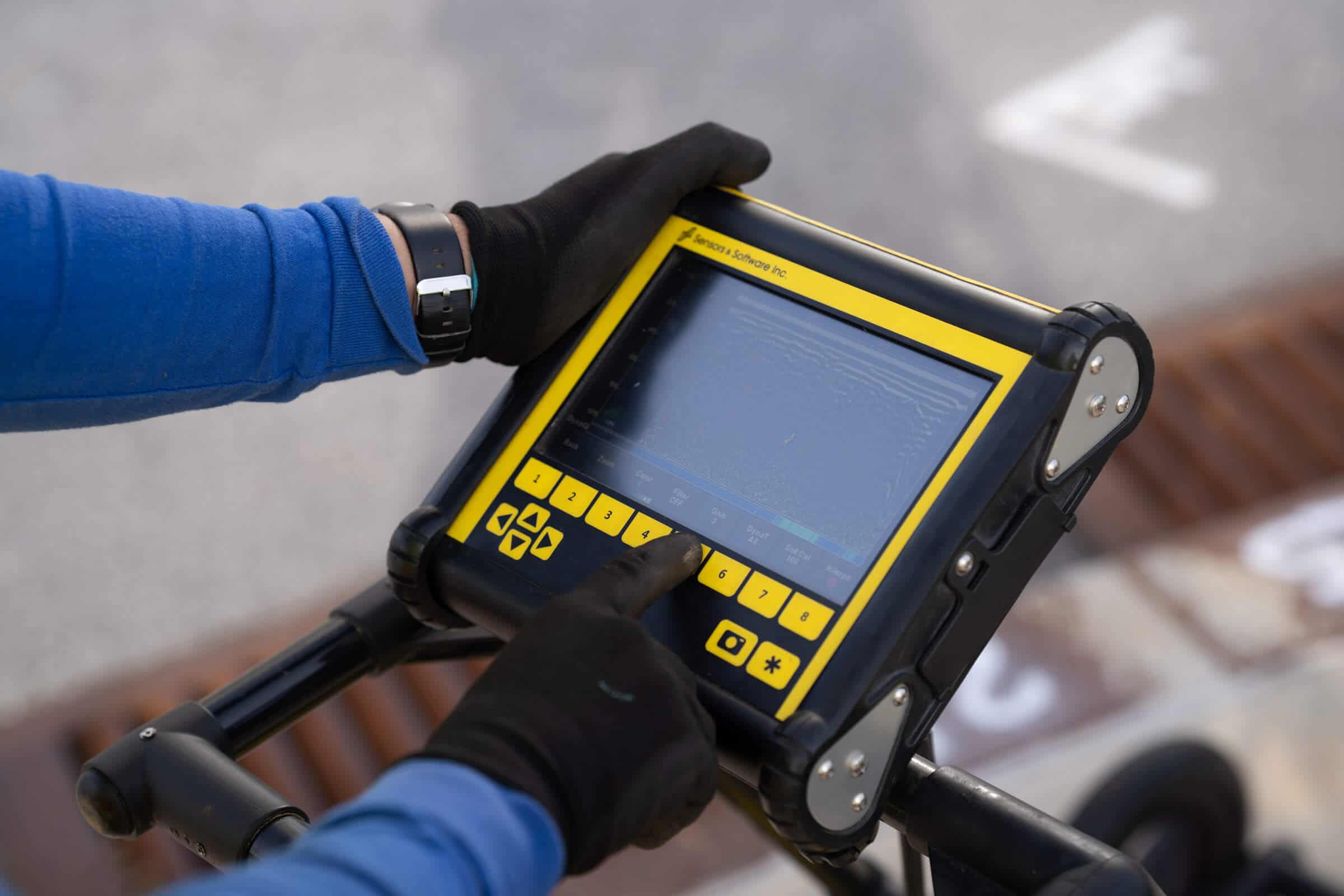 Screen of a GPR unit with a hand pressing a button on it