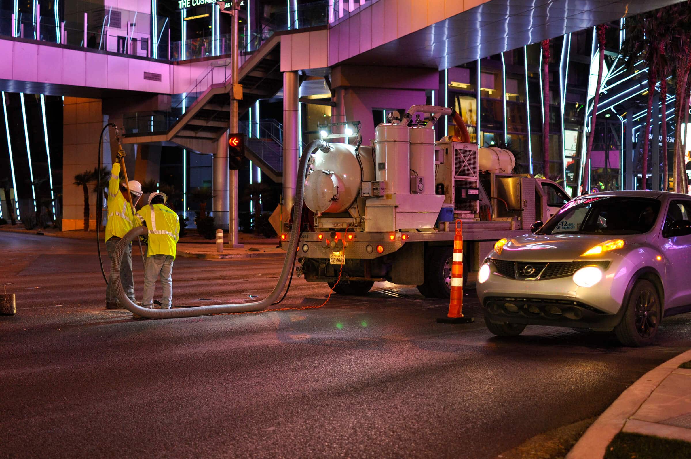 Two workers performing vacuum excavation at night on the Las Vegas strip