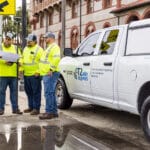 Group of 4 T2ue field workers having a safety meeting next to a T2 Utility Engineers pickup truck