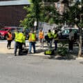 People wearing safety vests gathered around SUE equipment on an urban sidewalk